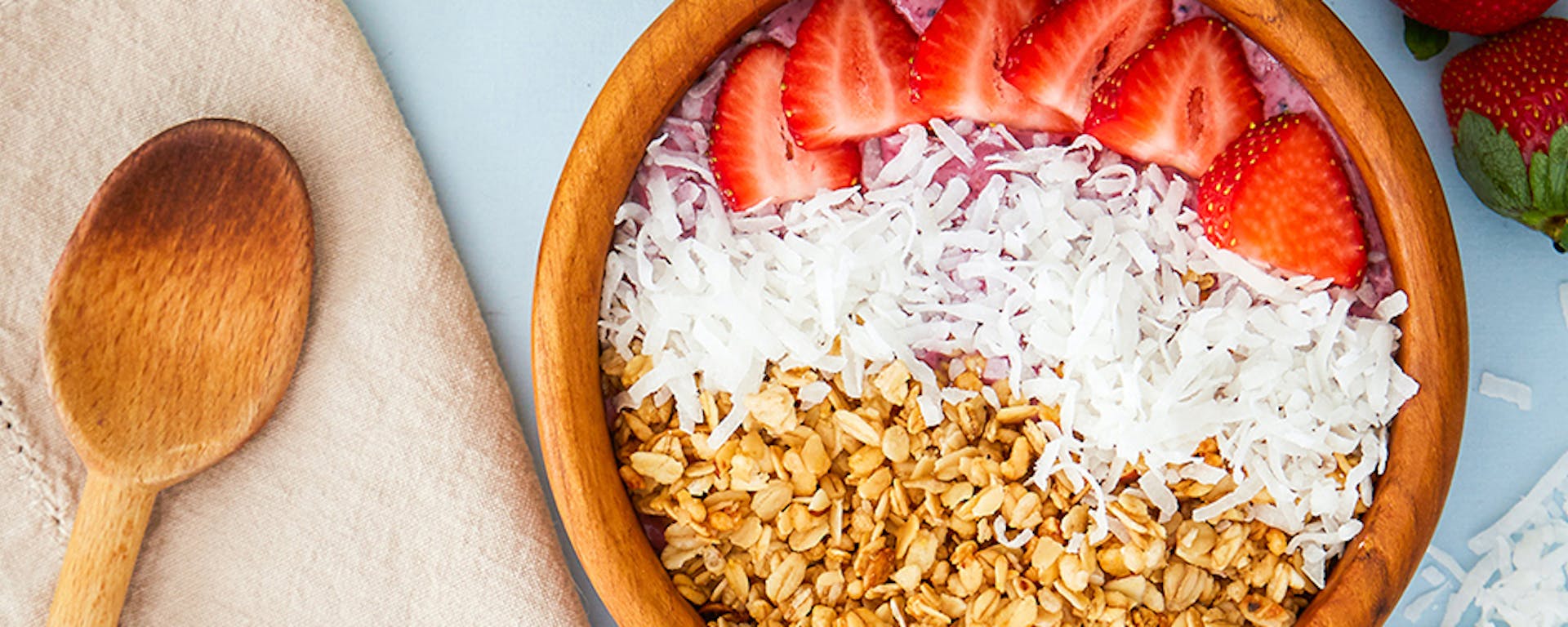 A bowl of strawberries, coconut and grains.
