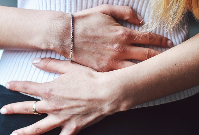 A person with their hands on their stomach as if they are in pain.