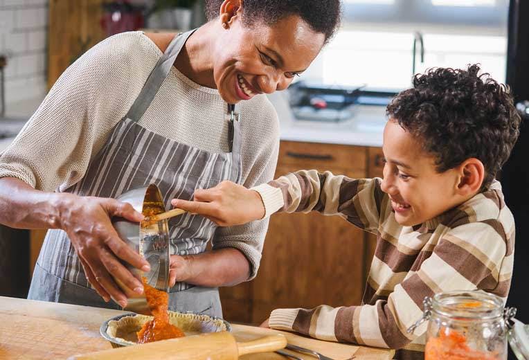 A mother and her young son in their kitchen, baking.