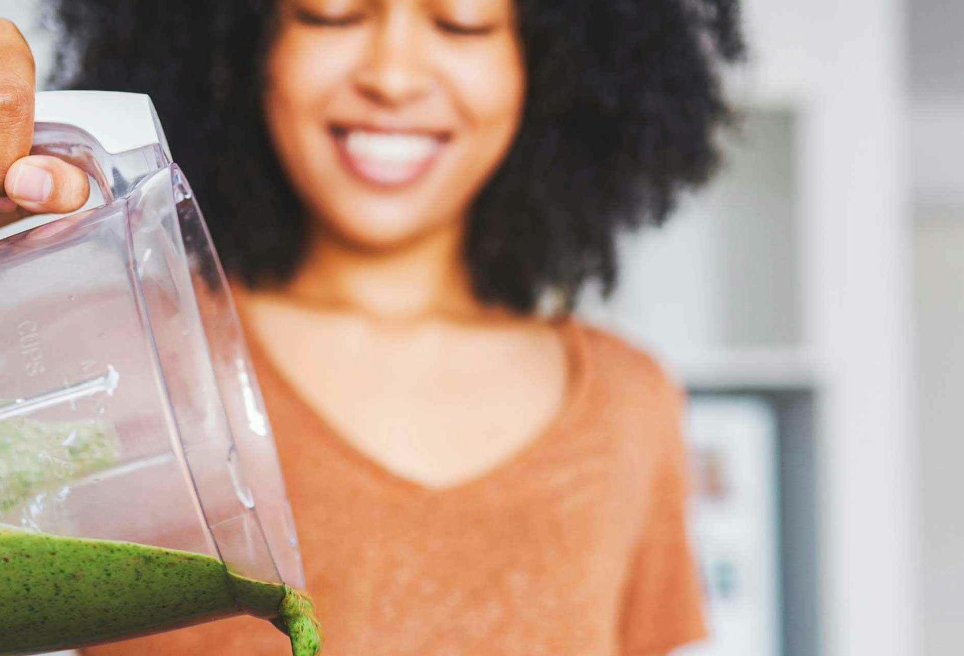 A women pouring a smoothie out of a blender.