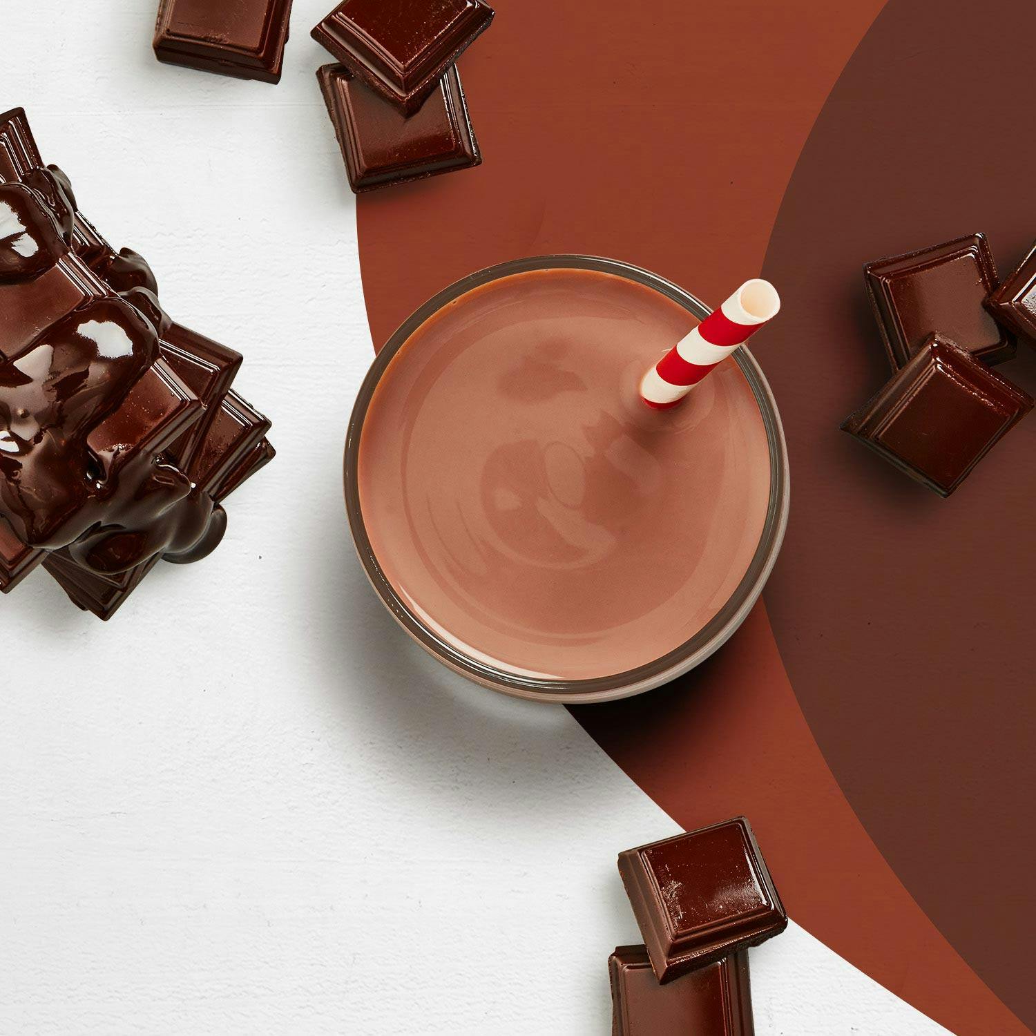 A chocolate Premier Protein shake surrounded by pieces of chocolate.