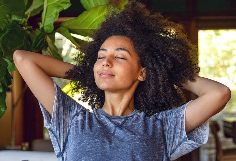 A women relaxing with her hands behind her head.
