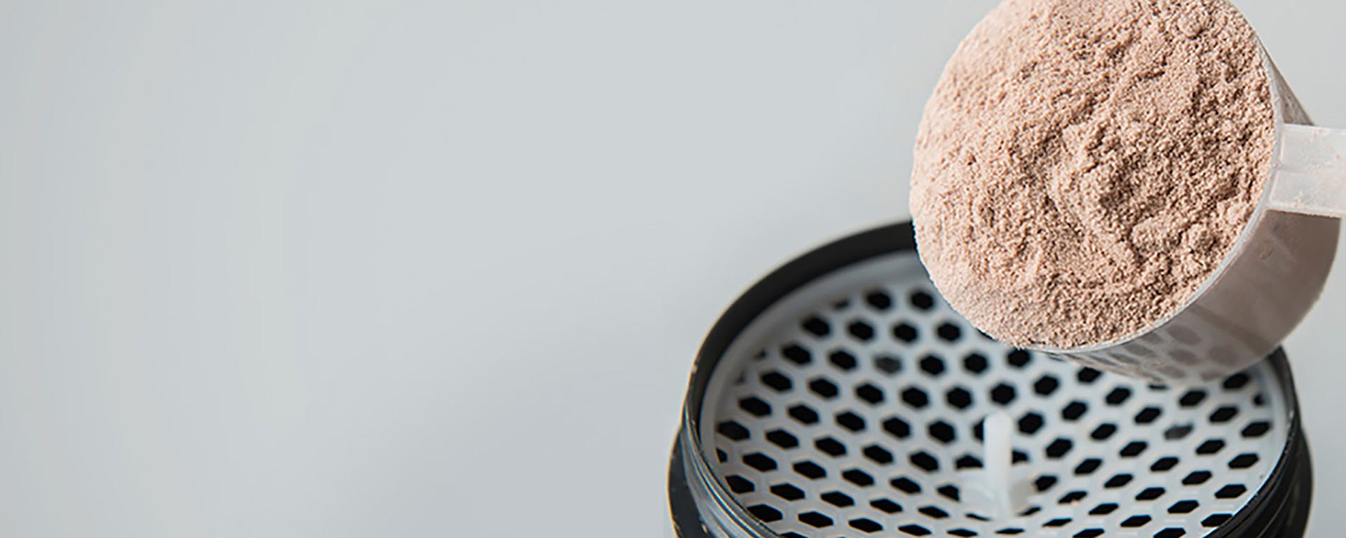 Protein powder being poured into a blender.