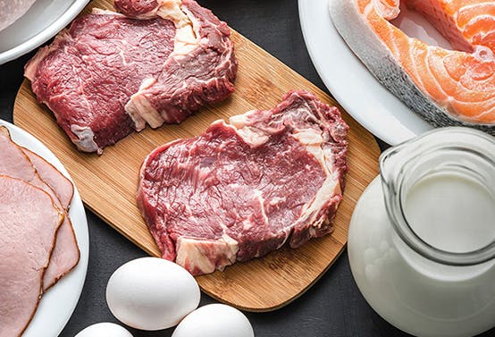 Plates full of meat, fish and a bowl of milk.